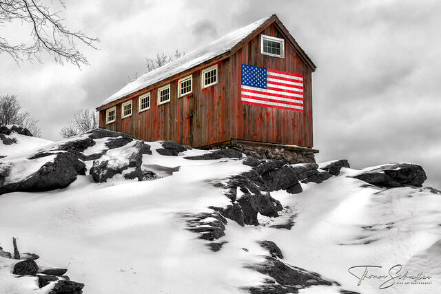 A stoic little red barn with an American flag high on a Litchfield county rock ledge | Iconic Grayledge farm scene by Thomas Schoeller Photography
