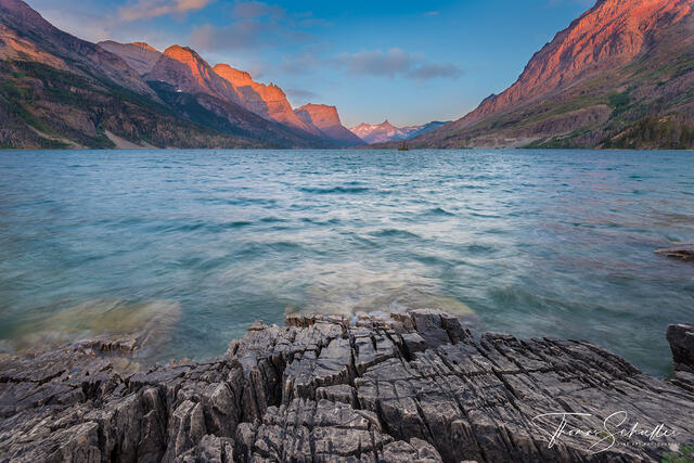 Turquois Waters of St Mary's lake below the soft alpenglow illuminating the Lewis Range in Glacier National park Montana