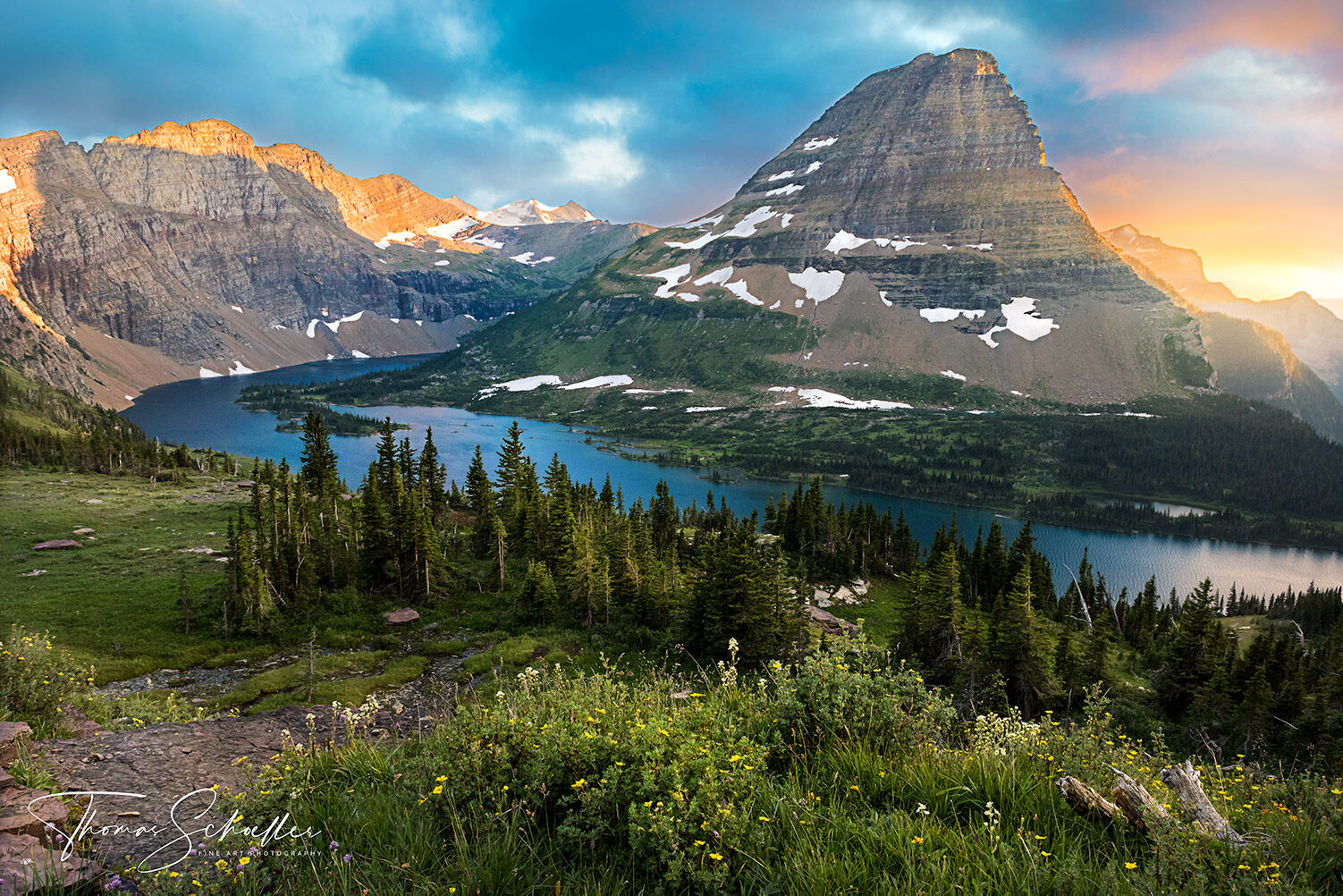 Viewed from Logan pass, Bearhat Mountain soars over Hidden lake as late-day summer storms depart, allowing dramatic sunset light to illuminate the highest peaks