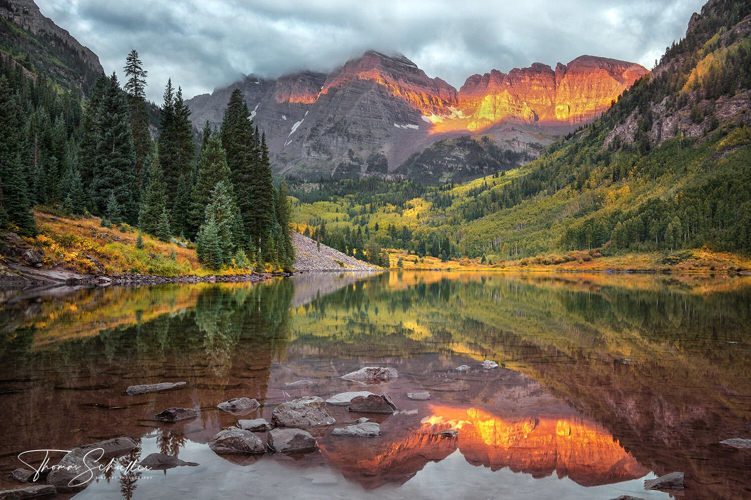 Stunning autumn sunrise at the Maroon Bells reflected off the calm surface of Maroon lake | Snowmass Wilderness Colorado
